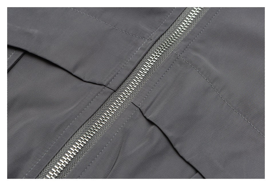 Close-up of gray garment fabric with a diagonal silver zipper and stitched seams.