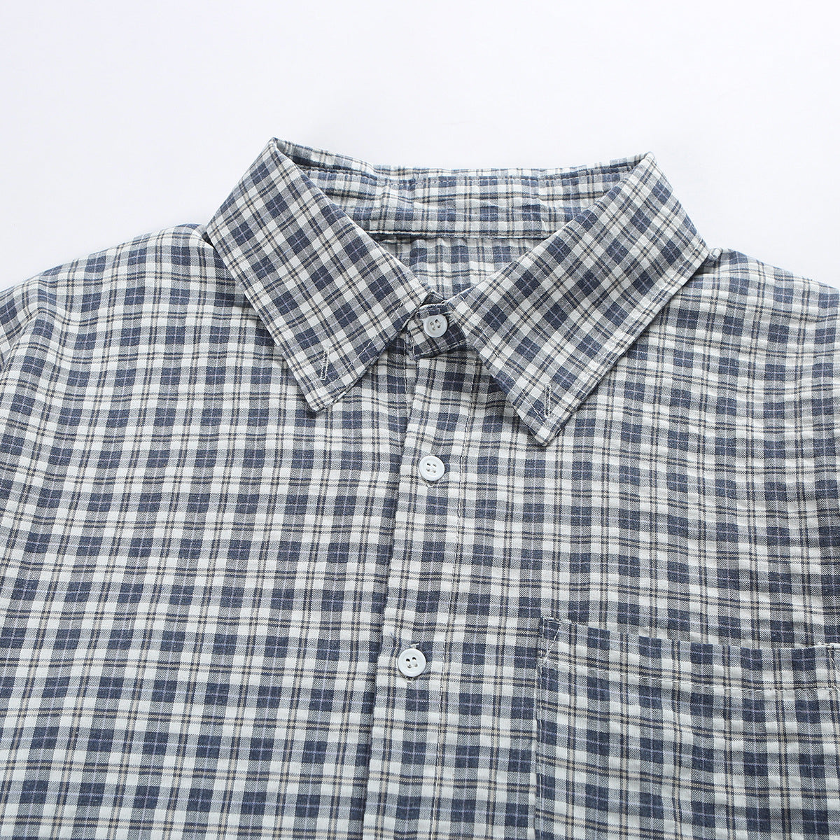 Close-up of a blue-gray and white plaid button-up shirt collar, buttons, and chest pocket.