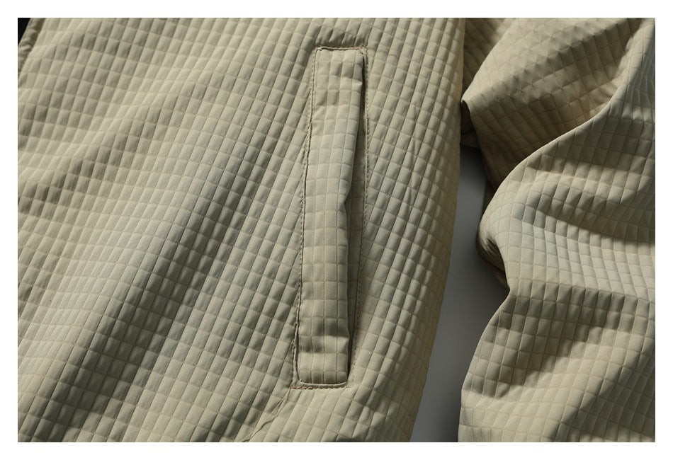 Close-up of a beige quilted jacket showing a vertical pocket opening and square stitching.