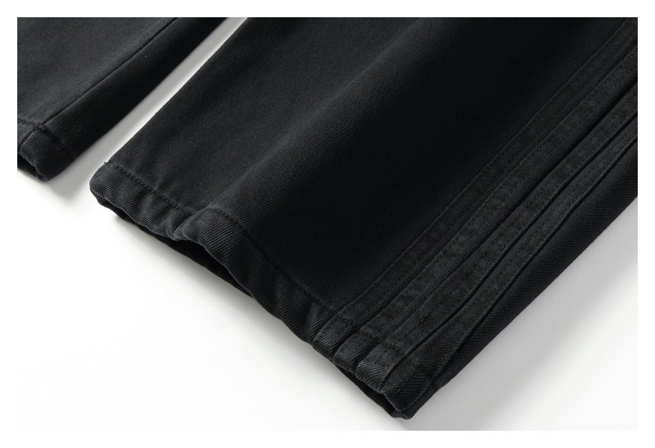 Close-up of a black trouser leg hem and parallel side stitching.