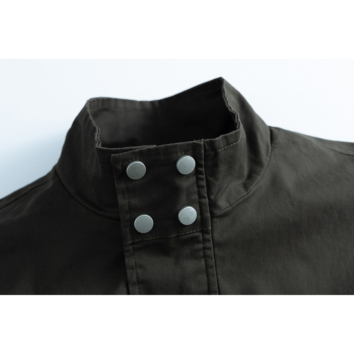 Close-up of a dark jacket’s stand collar and front placket with four silver snaps.
