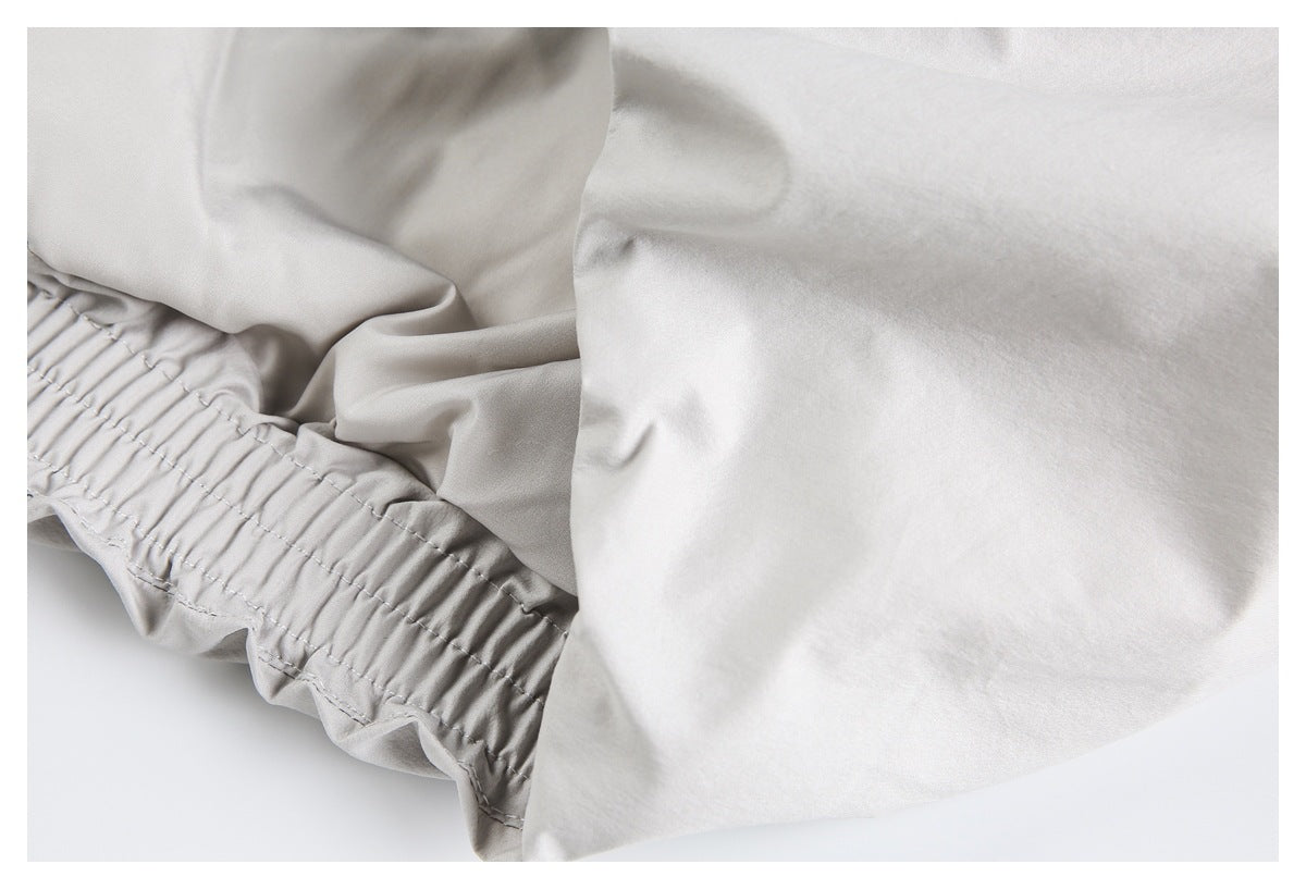 Close-up of a gathered elastic edge and stitched seams on a pale gray garment.