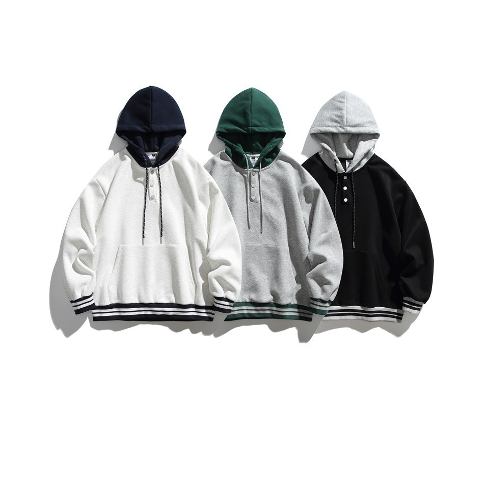 Three pullover hoodies shown together in white with navy trim, gray with green trim, and black with gray trim.