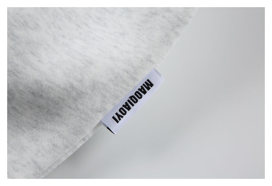 Close-up of a small woven label attached to the edge of light gray marled fabric.