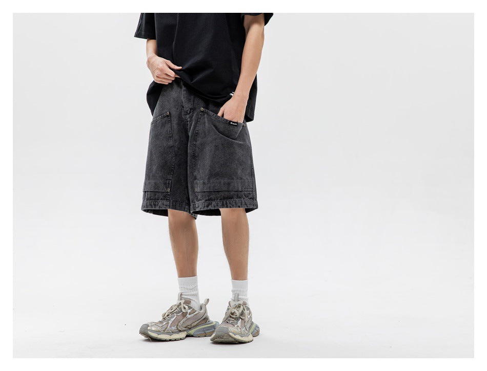 Person wearing black washed knee-length shorts with a black tee and chunky sneakers, hand in pocket, cropped at torso