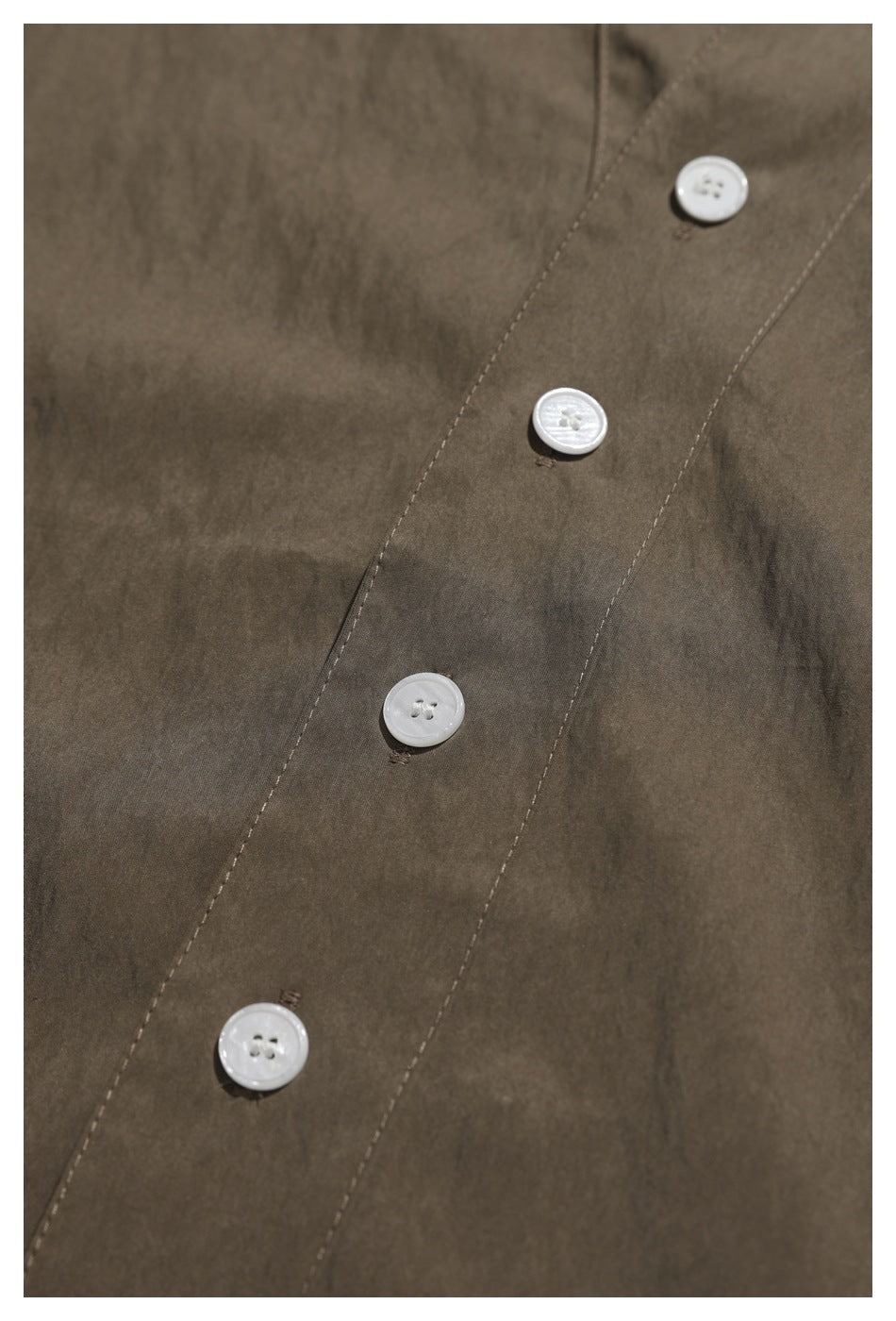 Close-up of four white buttons on the brown shirt's front placket.
