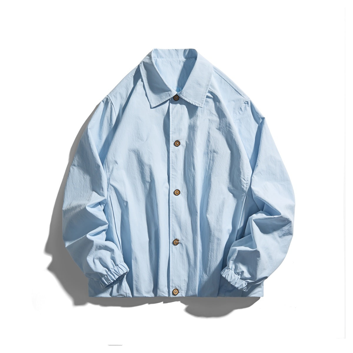 Light blue button-front jacket with pointed collar, elastic cuffs and light brown buttons, flat lay