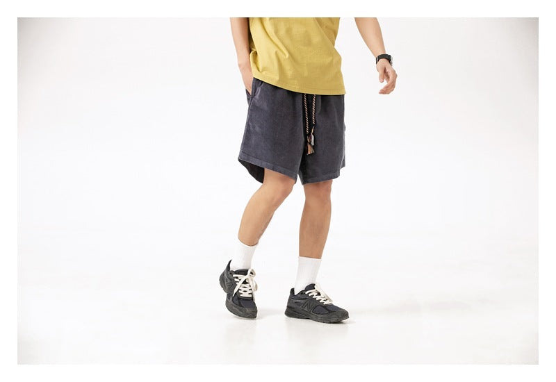 Cropped model wearing charcoal loose shorts with a hanging drawstring, shown at a three-quarter angle.