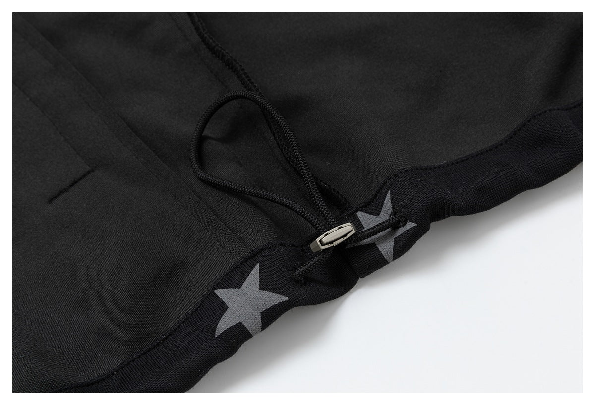 Close-up of a black garment's adjustable drawcord and metal toggle at the hem, with gray stars.