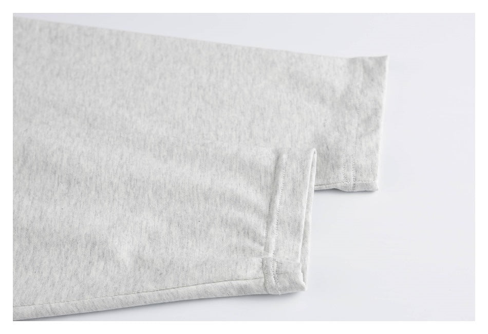 Close-up of the sleeve and stitched hem on a light gray heather garment.