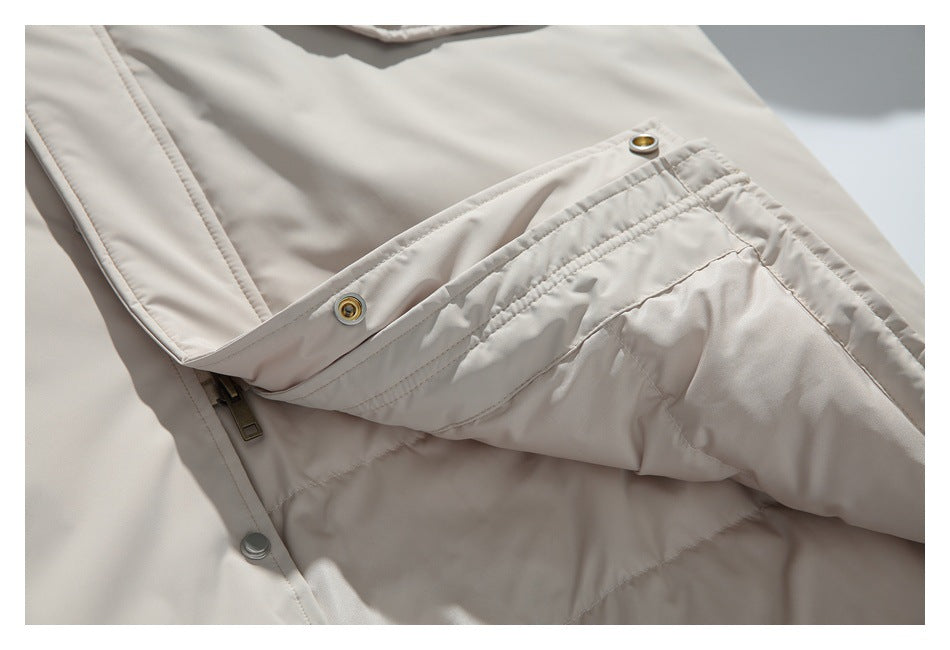 Close-up of a light beige jacket opening with snaps, zipper, and stitched panels.