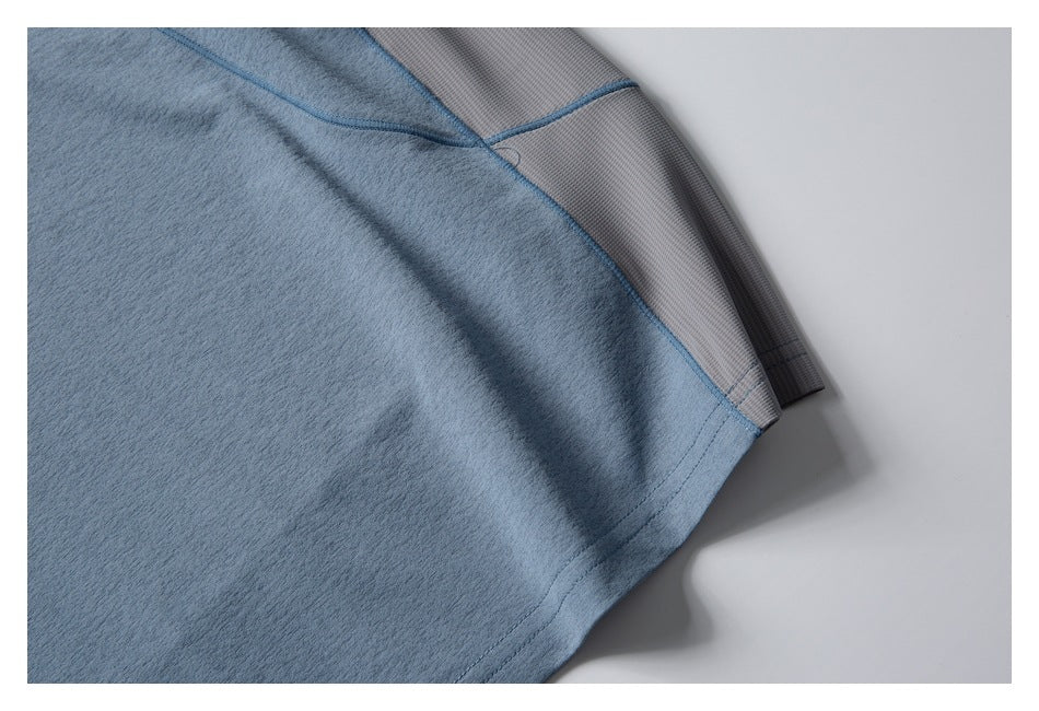 Close-up of blue garment fabric and a gray textured panel joined by blue stitching.
