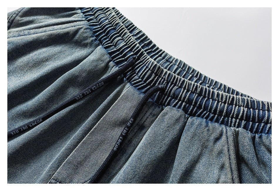 Close-up of blue denim shorts showing the gathered elastic waistband and stitched seams.