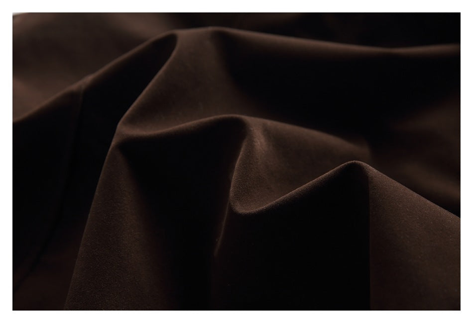 Close-up of dark brown fabric draped into folds, showing its surface and texture.