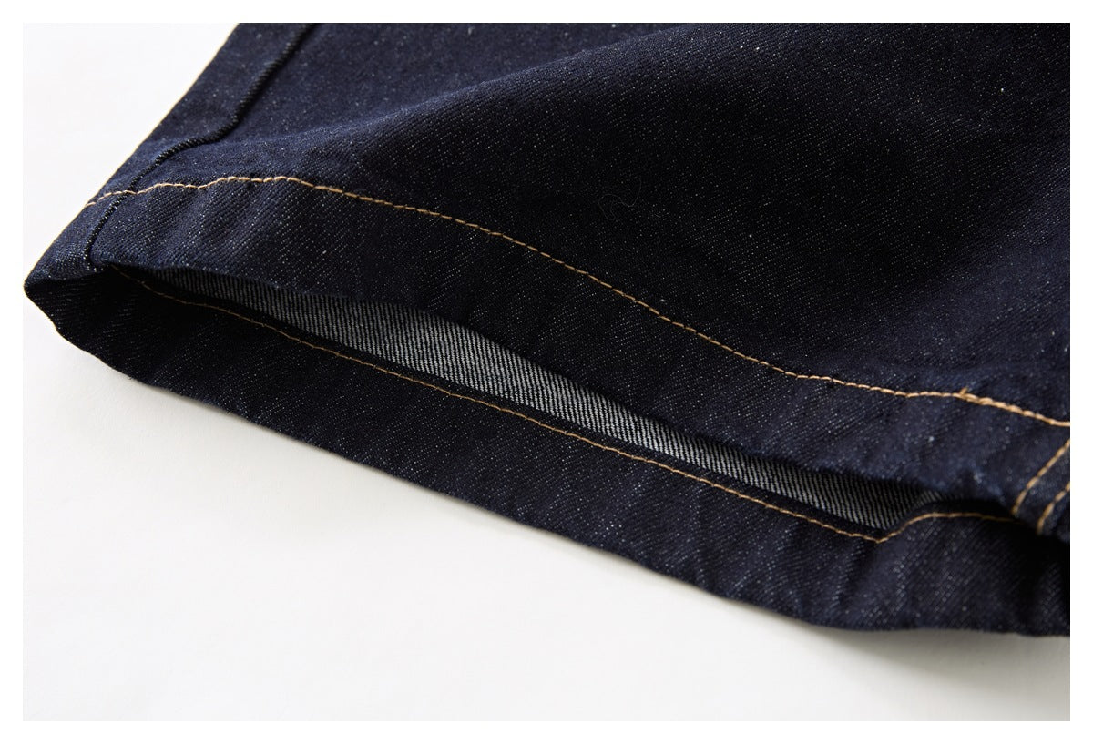 Close-up of a dark indigo denim hem turned back to show the inner weave and tan stitching.