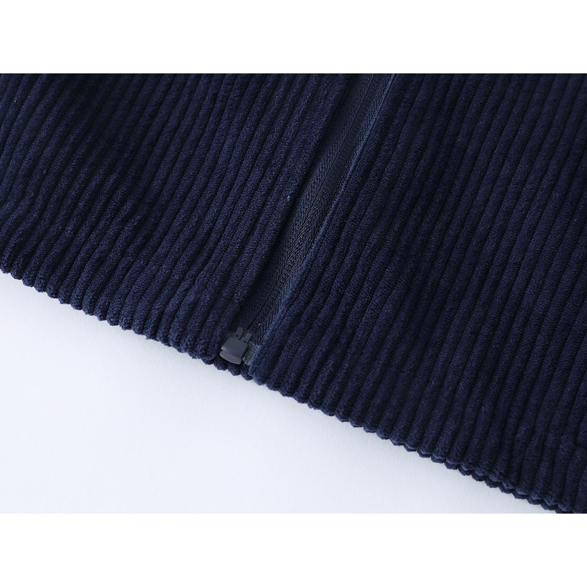 Close-up of the navy ribbed jacket's lower hem and zipper end.
