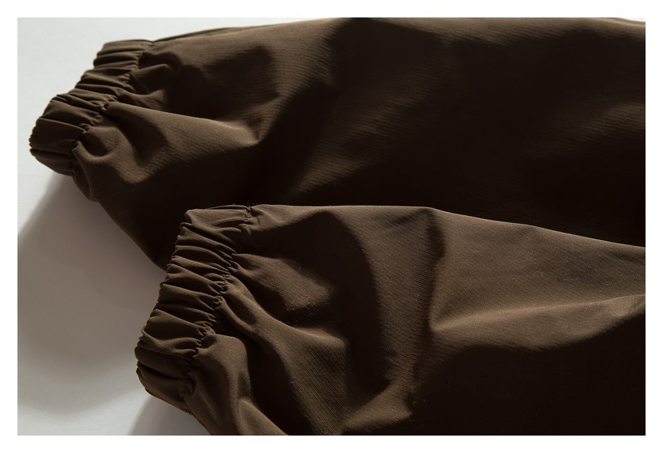 Close-up of two dark brown jacket sleeves with gathered elastic cuffs.
