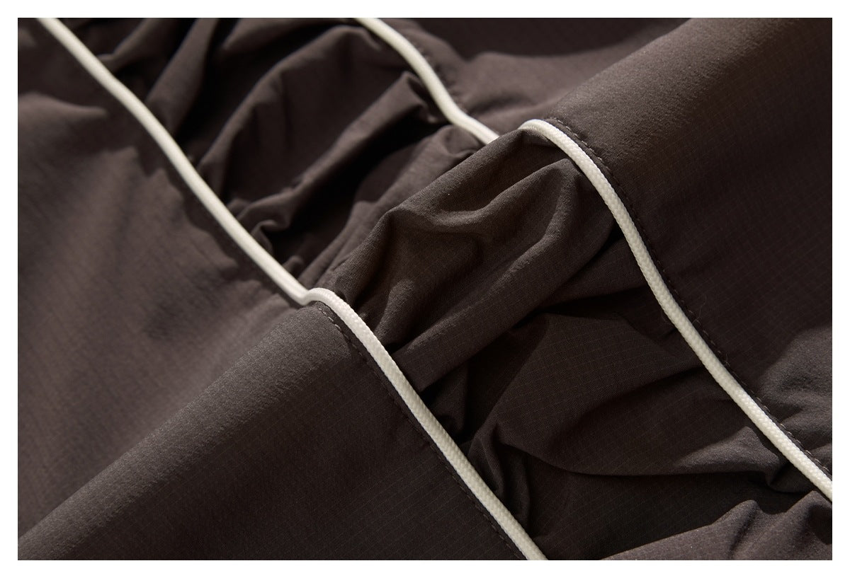 Close-up of dark brown garment panels joined with cream piping and visible stitching.