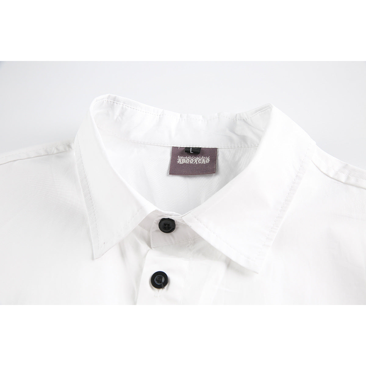 Close-up of a white shirt collar with black buttons and a sewn-in neck label.