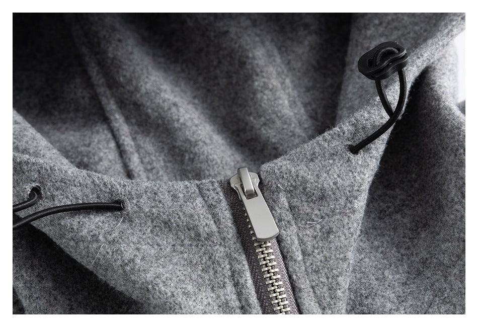 Close-up of a gray coat with a metal zipper and black drawcord toggles.
