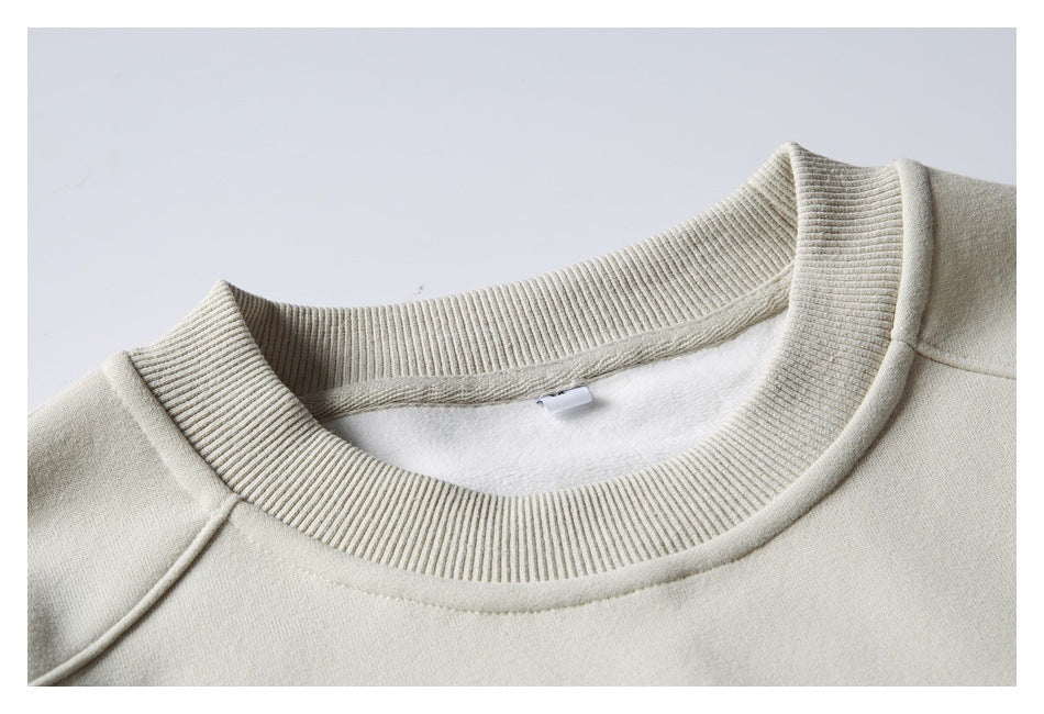 Close-up of a light beige sweatshirt's ribbed crew neck and soft white inner lining.