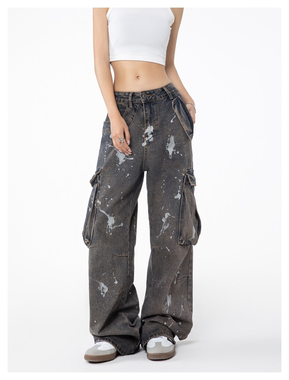 Front view of a model wearing loose charcoal-gray splatter-print cargo jeans with large side pockets.