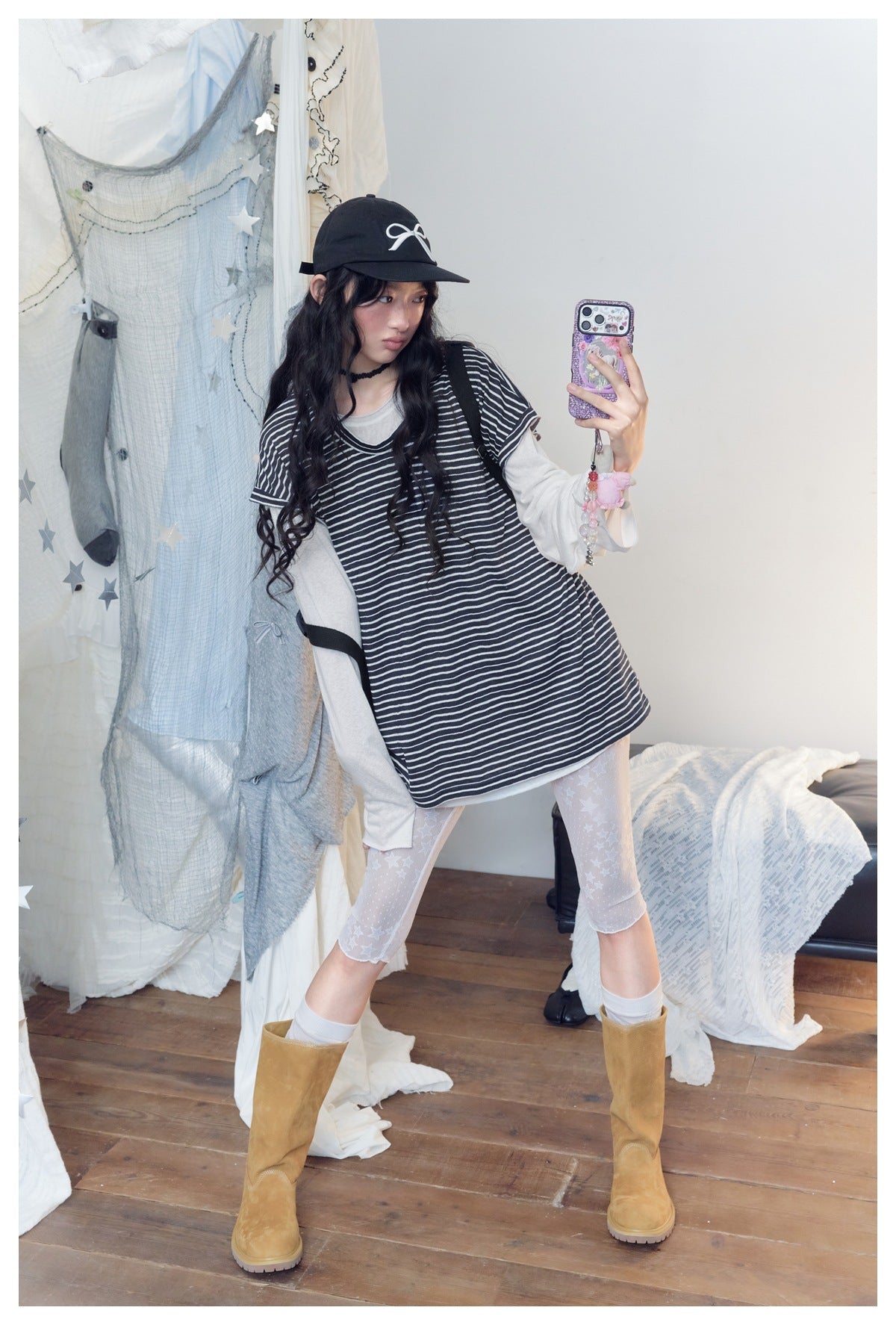 Model posing in a loose black-and-white striped short-sleeve top layered over a light long-sleeve shirt.