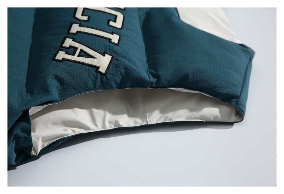 Close-up of the vest's lower edge, showing dark teal outer fabric and cream inner lining.