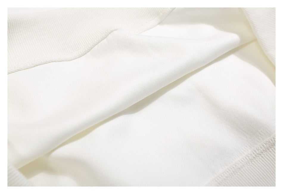 Close-up of white fabric with a folded edge and ribbed stitching.