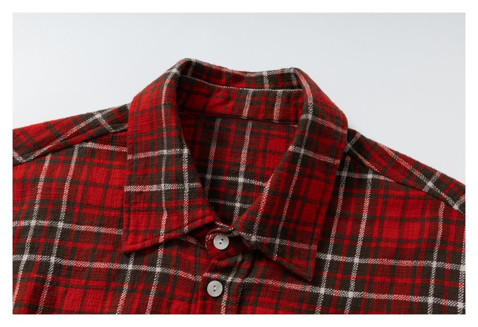 Close-up of the pointed collar and white buttons on a red plaid shirt.