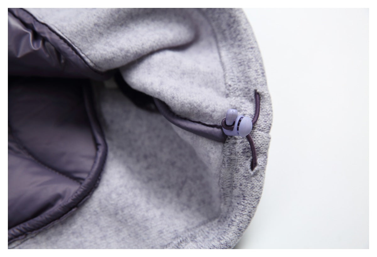 Close-up of a light gray heather jacket edge with a dark drawcord and plastic toggle beside the quilted lining.