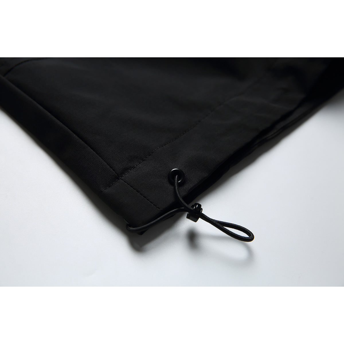 Close-up of a black jacket hem with an adjustable elastic drawcord.