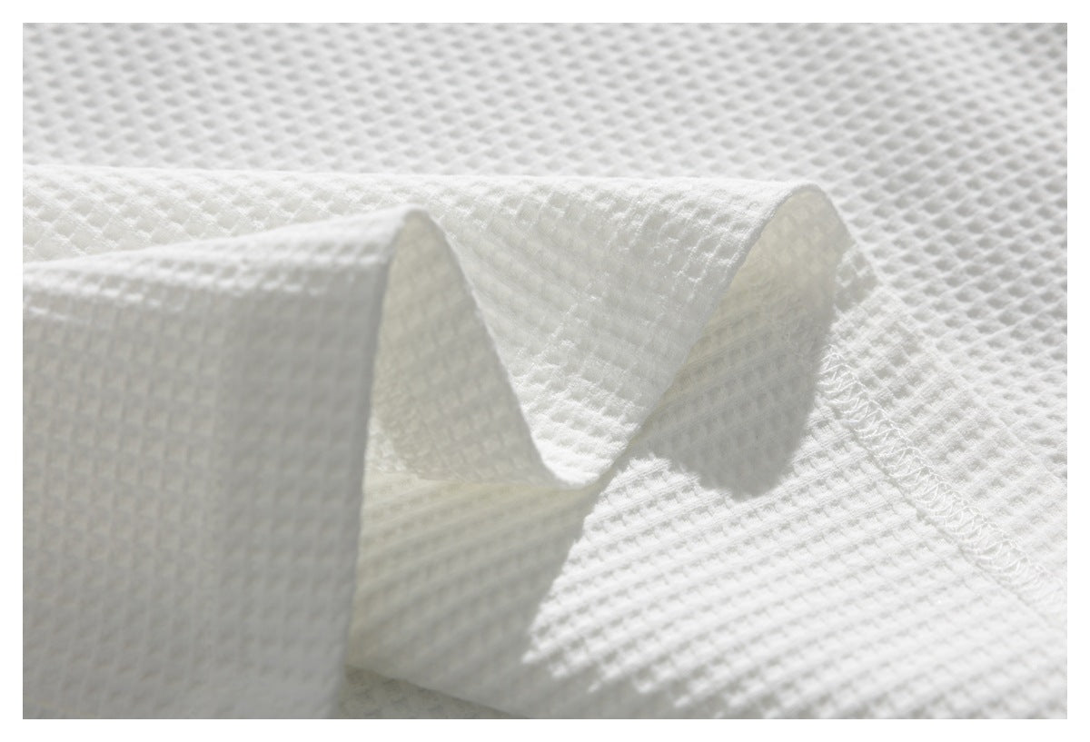 Close-up of white textured fabric showing a folded seam and stitching.