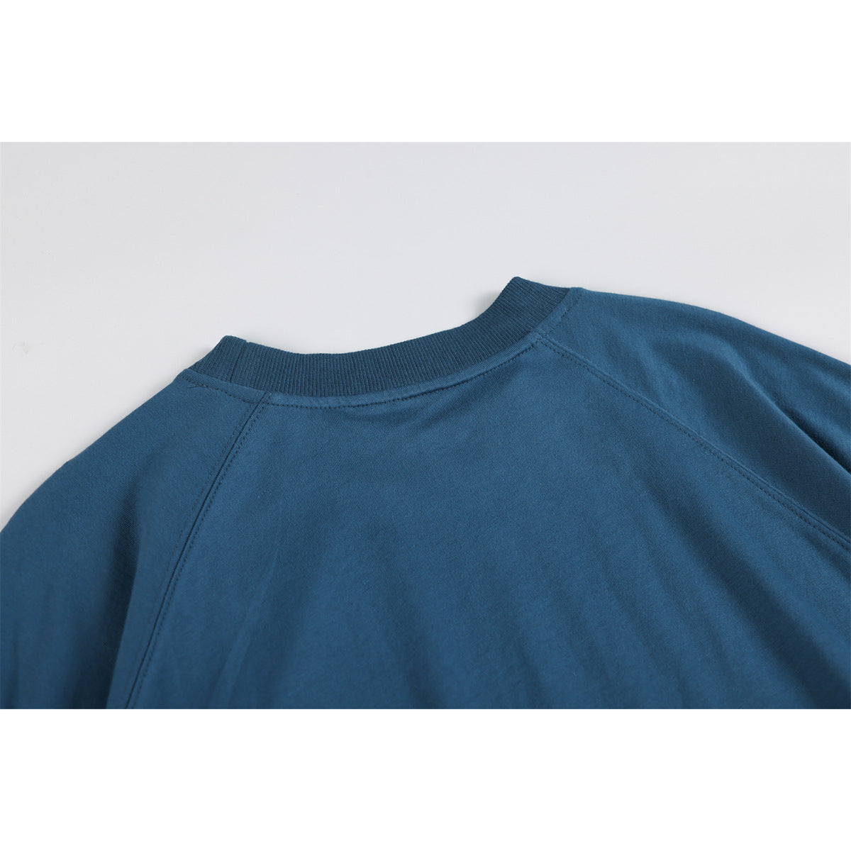 Close-up of the blue top's ribbed back neckline and raglan shoulder seams.
