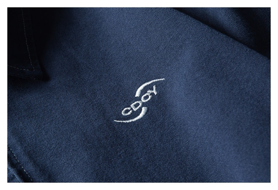 Close-up of a small white embroidered emblem on dark navy fabric.