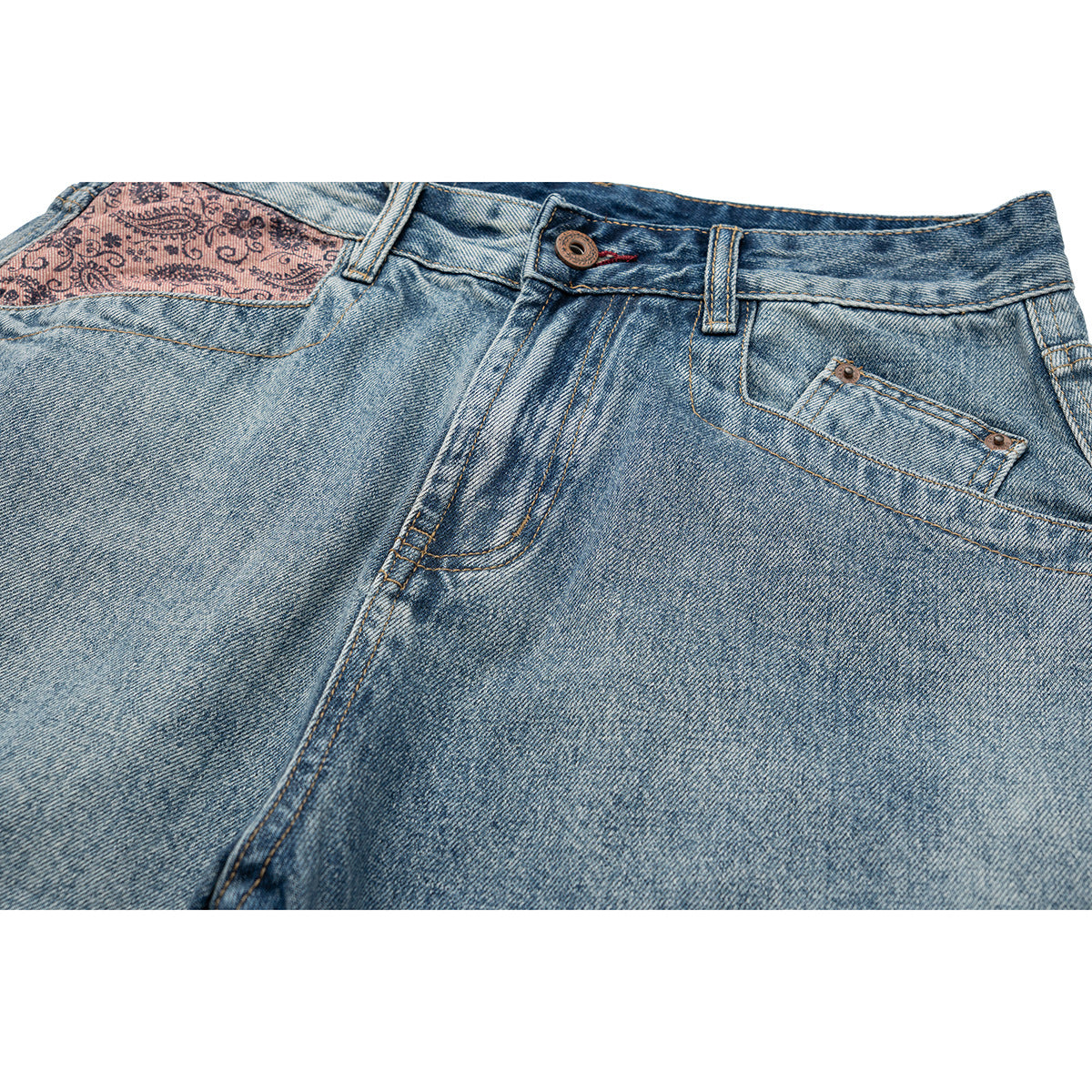 Close-up of light blue jeans showing the waistband, button, front pocket stitching, and pink paisley pocket lining.