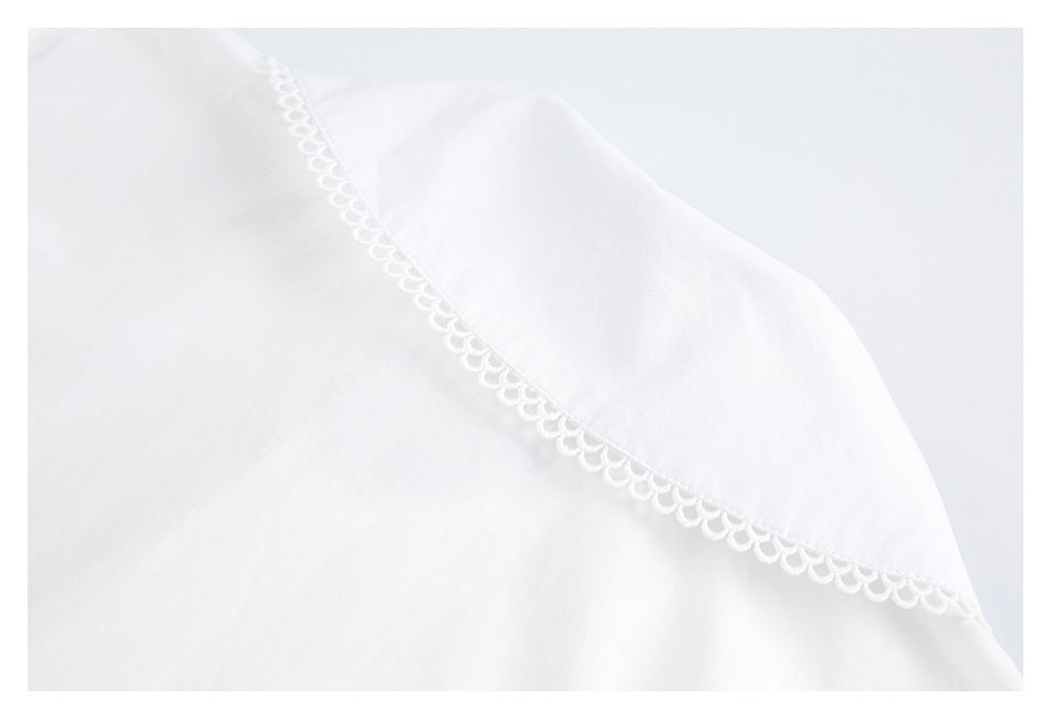 Close-up of white garment fabric with decorative scalloped trim along a curved seam.