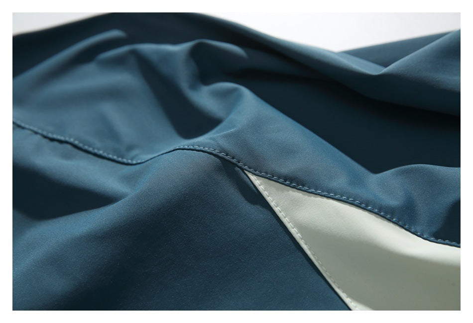 Close-up of a curved stitched seam and ivory insert on dark teal fabric.