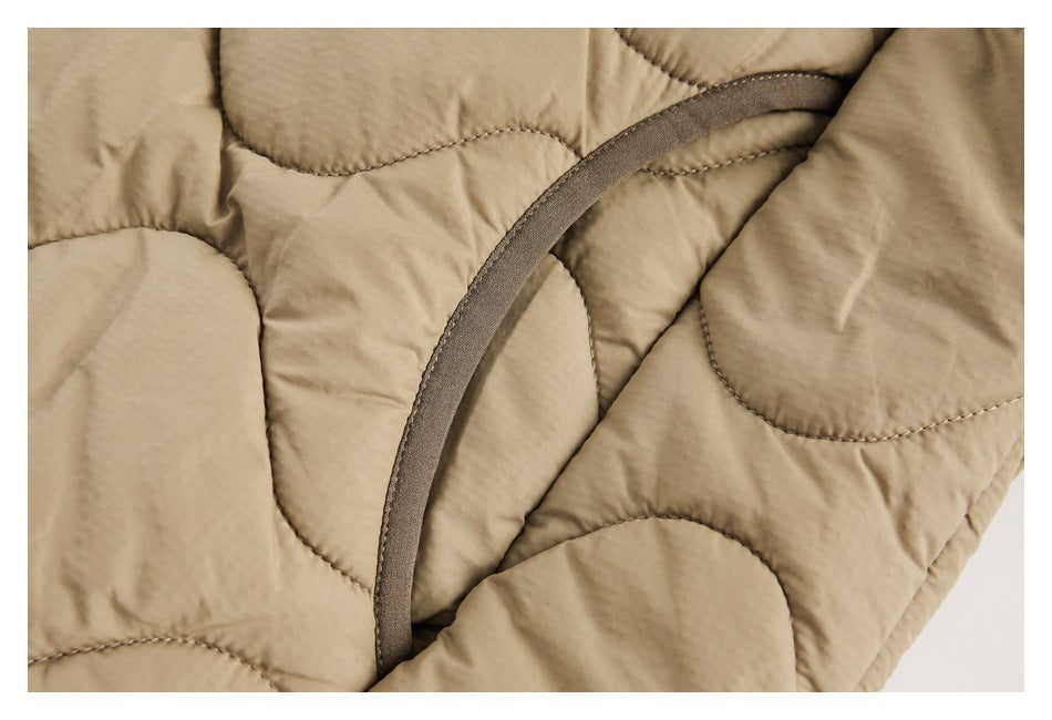 Close-up of tan quilted fabric and curved dark brown binding along an opening.
