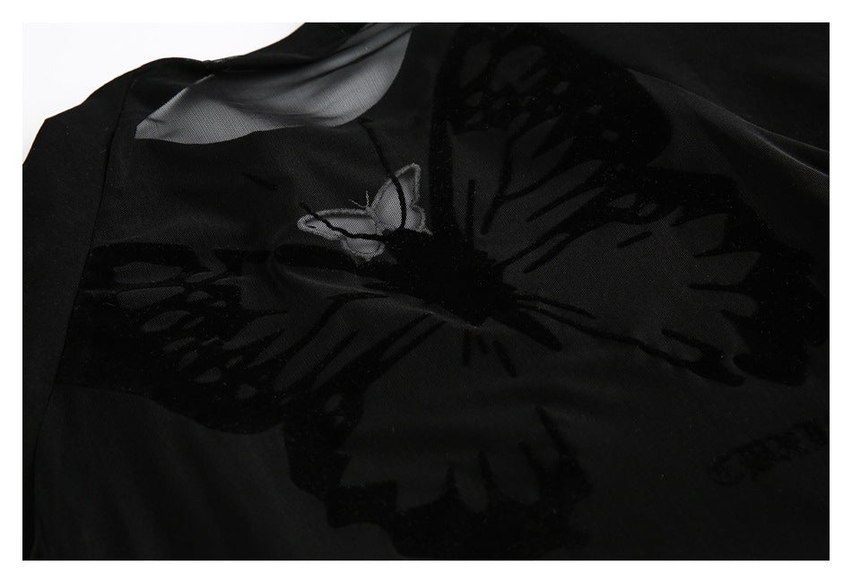 Close-up of a black garment with a dark butterfly motif over sheer mesh panels.