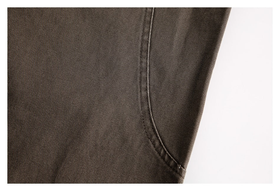Close-up of brown trouser fabric and a curved seam against a white background.