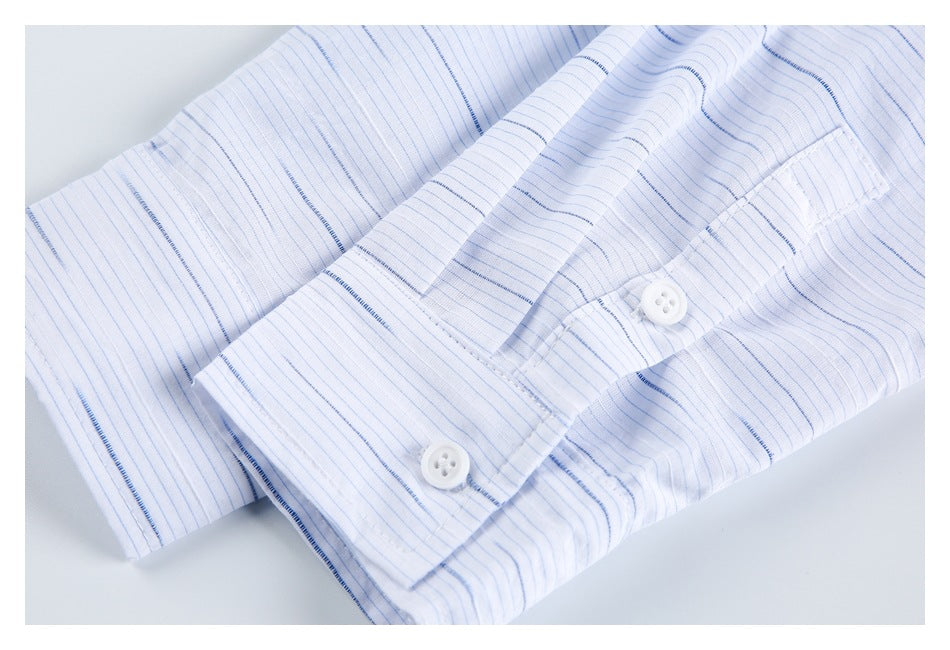 Close-up of a white shirt cuff with two buttons and fine blue stripes.