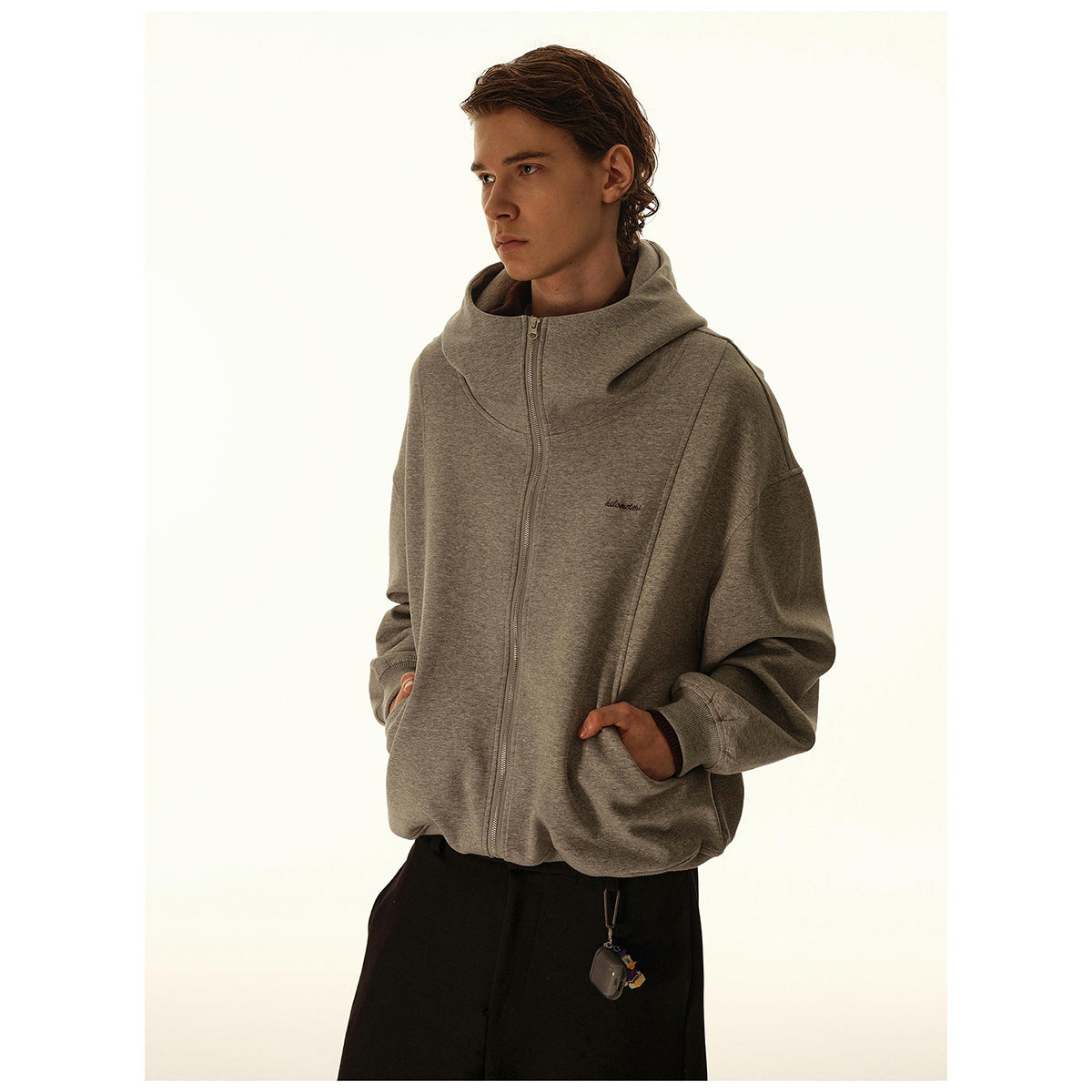Model wearing a gray zip-up hooded jacket with roomy sleeves and front pockets.