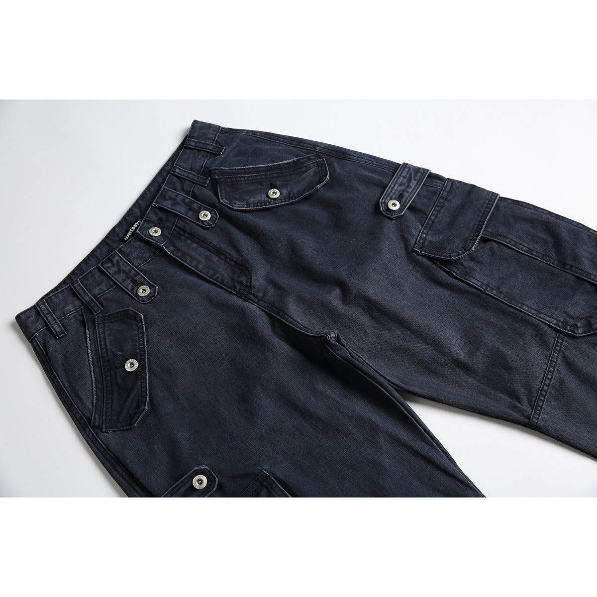 Angled flat lay of dark navy cargo pants with multiple buttoned flap pockets and contrast stitching.