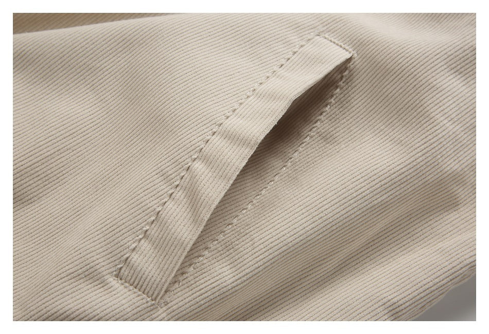 Close-up of a slanted welt pocket on the cream corduroy jacket.