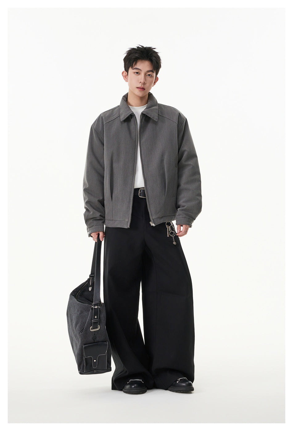 Full-length view of a model wearing a gray zip-front jacket with a pointed collar and black wide-leg trousers.