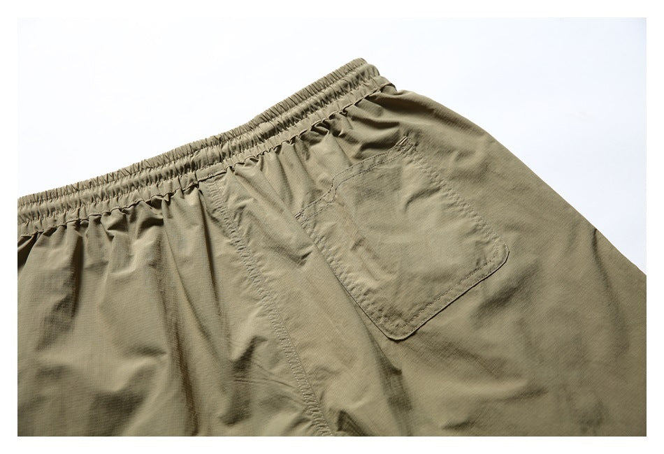 Cropped rear view of olive-khaki shorts laid flat, showing the elastic waistband and a patch pocket.