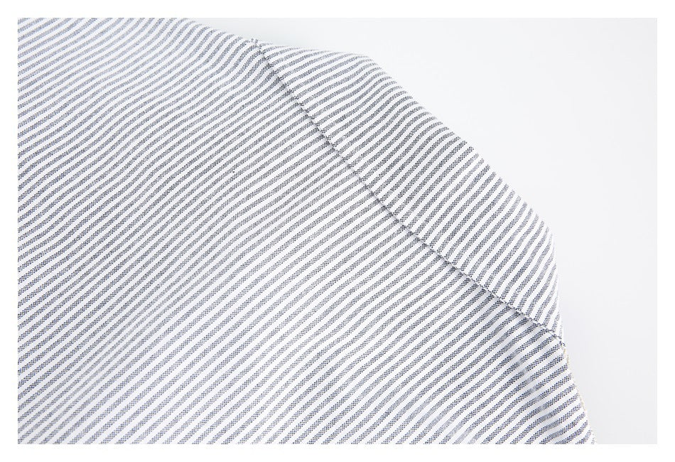 Close-up of a curved stitched seam across white fabric with fine navy stripes.