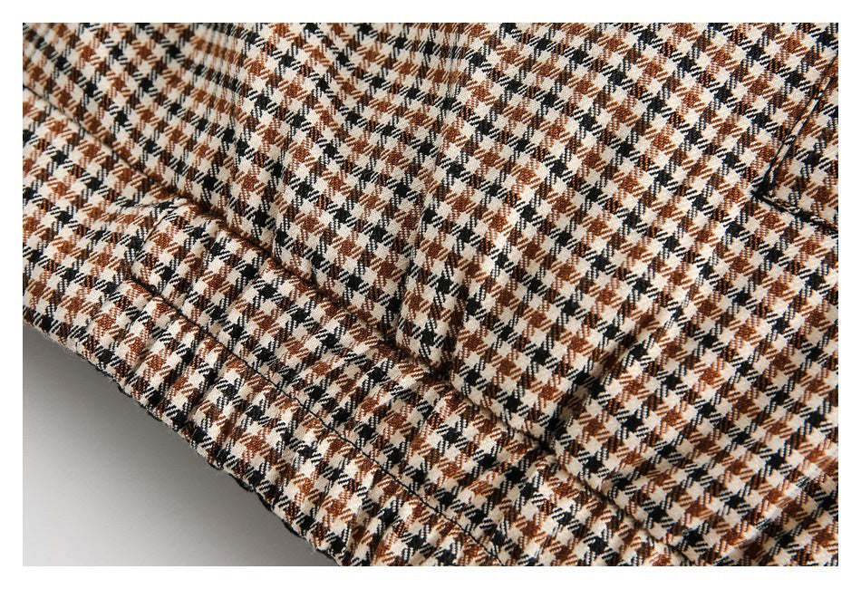 Close-up of stitching and a folded edge on brown, black, and cream houndstooth fabric.