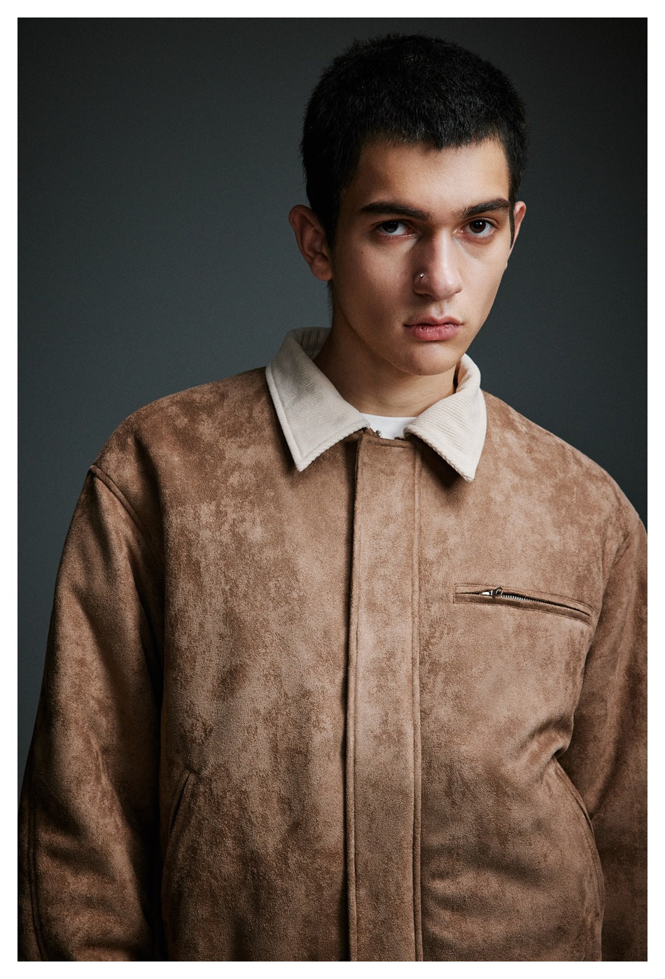 Close-up of a model wearing a tan jacket with a cream collar and zippered chest pocket.